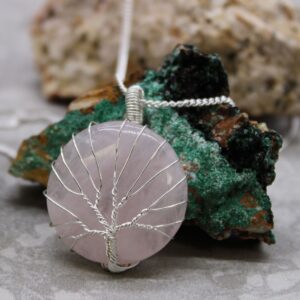 Delicate rose quartz gemstone in a tree of life cage necklace.