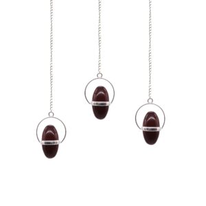 Shiva Lingam with Band Pendulum resting on a soft surface.
