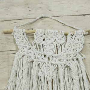 Handcrafted macrame wall hanging featuring a unique tribal design.