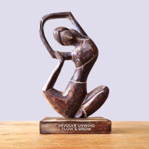 Antique wooden yoga lady figurine in revolved pose for mindful living.