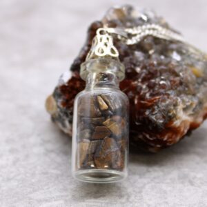 Necklace featuring a vial filled with tiny amethyst gemstones and a decorative cap.