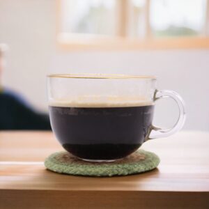 Set of four natural coasters with olive border made from jute and cotton.