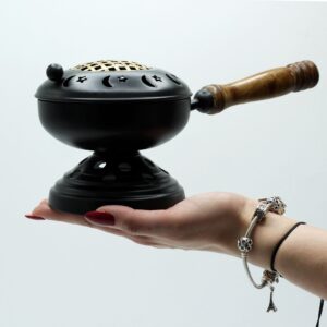 Large iron censer with gold accents on a sturdy stand for incense burning.