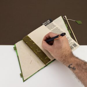 Moss green notebook with a botanical pattern and bamboo lock for secure closure.