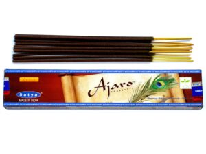 Satya Ajaro incense sticks in a decorative holder, releasing fragrant smoke.