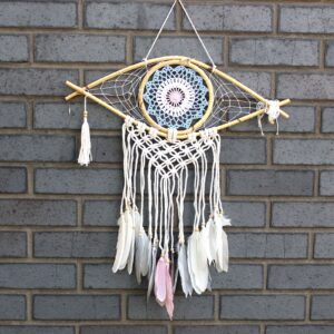 Handmade macrame dream catcher featuring an Evil Eye design in blue, white, and pink.
