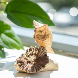 Hand-carved owl sculpture on a natural wood base, showcasing intricate details.