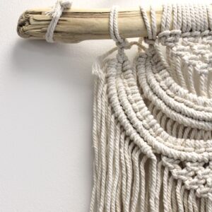 Handcrafted macrame wall hanging featuring two waves in a boho style.