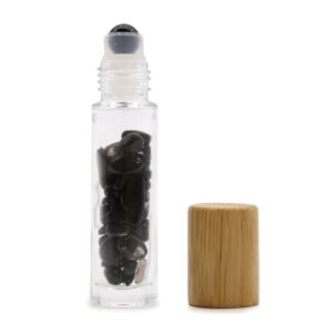 Black tourmaline essential oil roller bottle with wooden cap and gemstones inside.