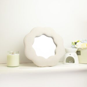Soft squiggly mirror in a flower shape with a stone-toned frame.