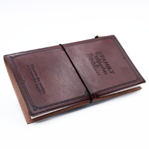 Handmade brown leather journal with embossed design and wrap-around band.