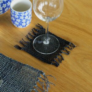 Handcrafted black seagrass coasters with fringe detailing for stylish decor.