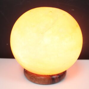 Himalayan salt lamp ball on a big wooden base, glowing warmly in a serene setting.