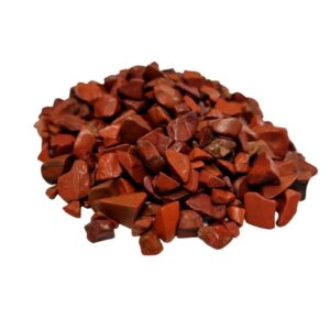 Bulk red jasper gemstone chips in a natural setting, ideal for crafting and decoration.