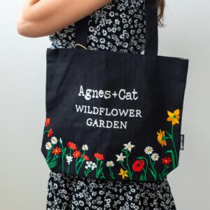 Black tote bag with embroidered wildflower design for stylish everyday use.