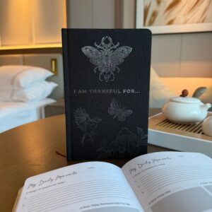 Elegant black gratitude journal with silver lining and motivational cover design.