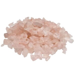 Bulk rose quartz gemstone chips in a natural setting, ideal for decoration.