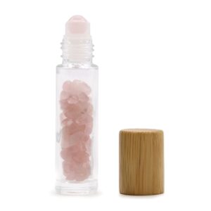 Rose quartz essential oil roller bottle with wooden cap and gemstones inside.