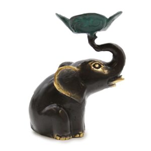 Small elephant candle and incense holder in a serene setting.
