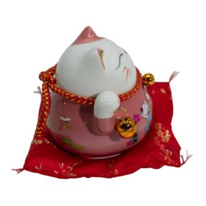 Pink ceramic Money Cat with a moving paw on a red decorative cushion.